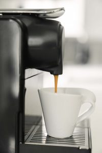 Espresso pouring into white coffee cup